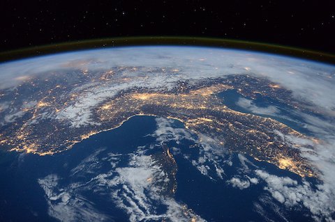 宇宙から見た地球の一部で夜間に街や道路の部分が光っている様子の写真